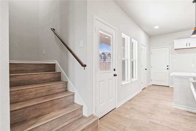 interior space with stairs, baseboards, and light wood finished floors