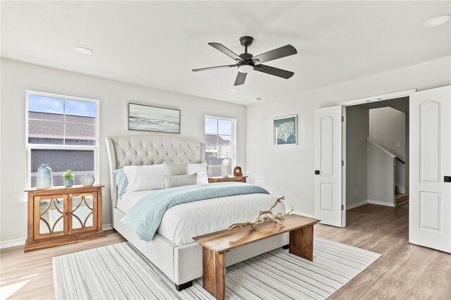 bedroom with a ceiling fan, light wood-style floors, and baseboards