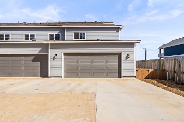 garage with concrete driveway and fence