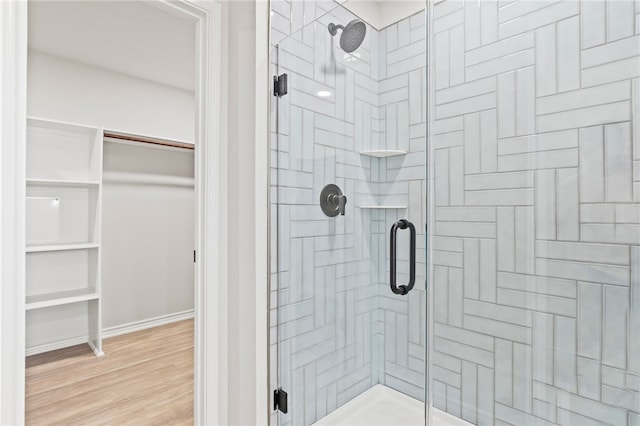 bathroom featuring a shower stall, baseboards, and wood finished floors