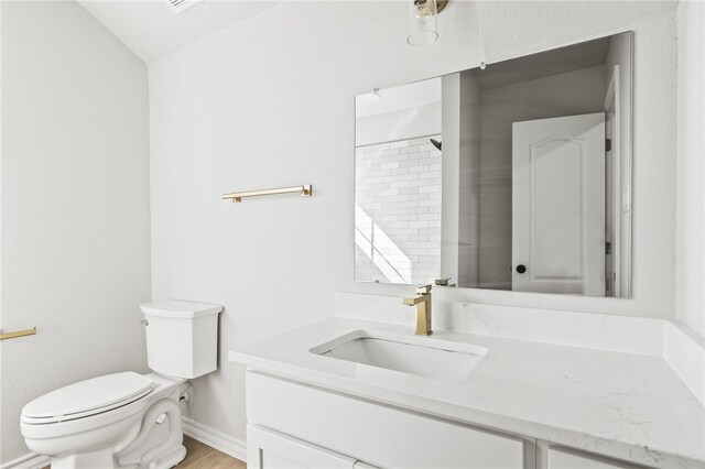 bathroom with toilet, vanity, baseboards, and wood finished floors