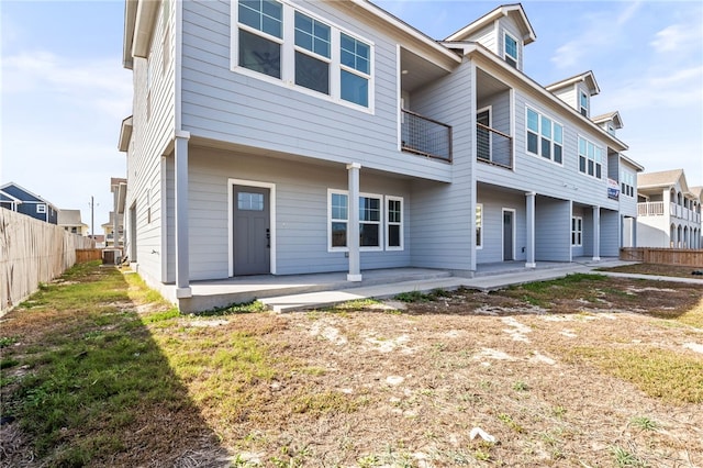 back of house with a balcony, a patio area, fence, and central AC