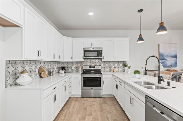 kitchen with white cabinets, backsplash, appliances with stainless steel finishes, and a sink