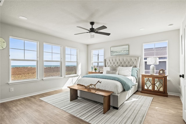 bedroom featuring light wood-type flooring, multiple windows, and baseboards