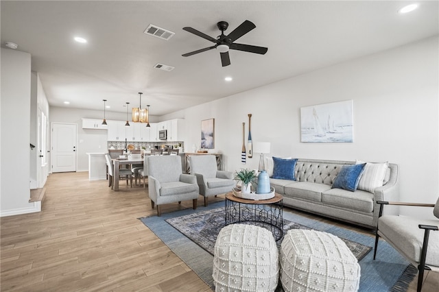 living room featuring recessed lighting, visible vents, light wood-style flooring, and ceiling fan with notable chandelier