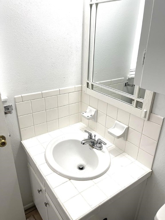 1403 Kingfisher Dr, Beeville, TX 78102 - bathroom featuring vanity, decorative backsplash, and a textured wall