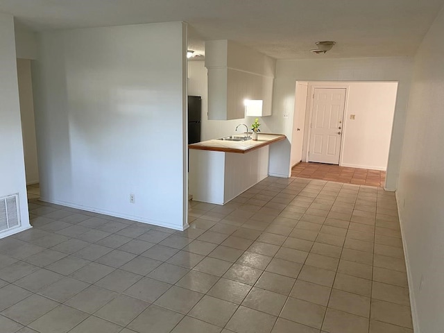 1403 Kingfisher Dr, Beeville, TX 78102 - kitchen featuring light tile patterned floors, light countertops, freestanding refrigerator, and white cabinetry