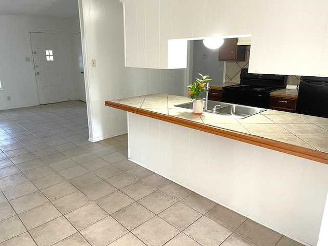 1403 Kingfisher Dr, Beeville, TX 78102 - kitchen featuring black range with electric stovetop, tile counters, light tile patterned floors, and white cabinetry