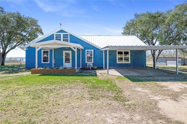 bungalow-style home with metal roof, a carport, a front yard, and stucco siding