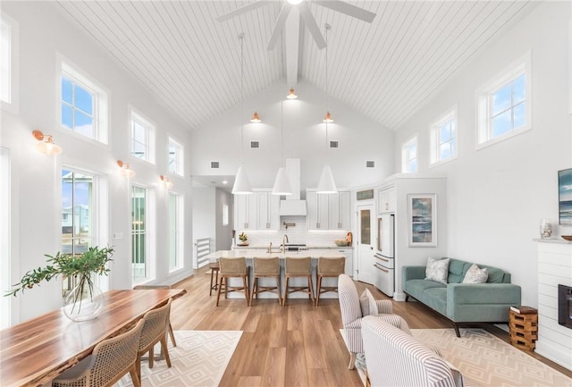 living area featuring light wood-type flooring, wood ceiling, a fireplace, and lofted ceiling with beams