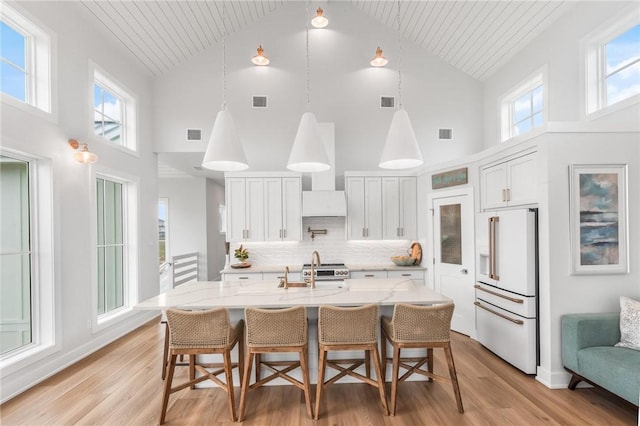 kitchen with premium appliances, light stone counters, and light wood finished floors