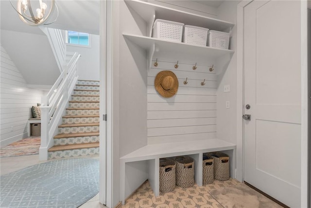 mudroom featuring a chandelier and wood walls