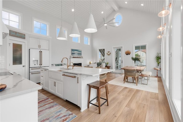 kitchen featuring white cabinets, white appliances, light wood finished floors, and a sink