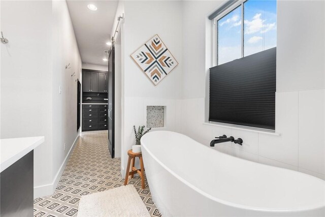 bathroom with tile patterned flooring, vanity, tile walls, a soaking tub, and a shower stall