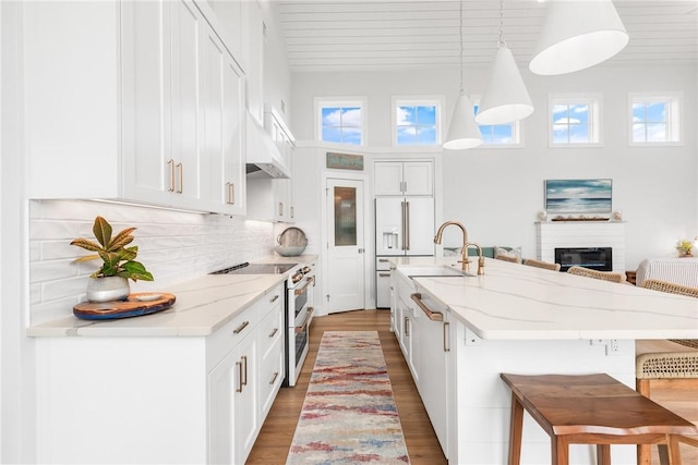 kitchen with premium appliances, light wood-type flooring, white cabinets, and a kitchen bar