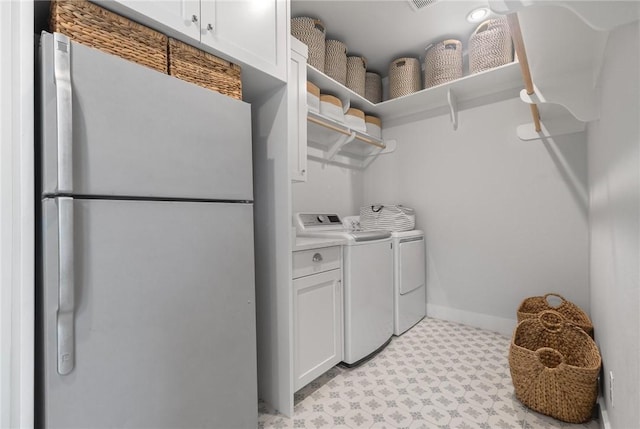 laundry room with cabinet space, baseboards, separate washer and dryer, and light floors