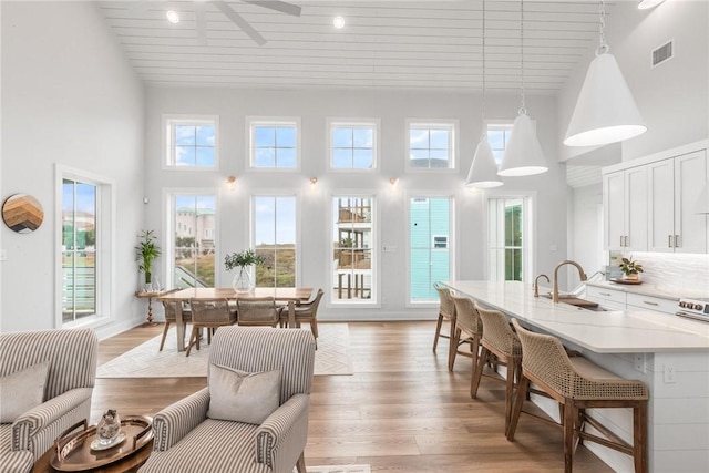 interior space featuring a towering ceiling, light wood-style flooring, and visible vents