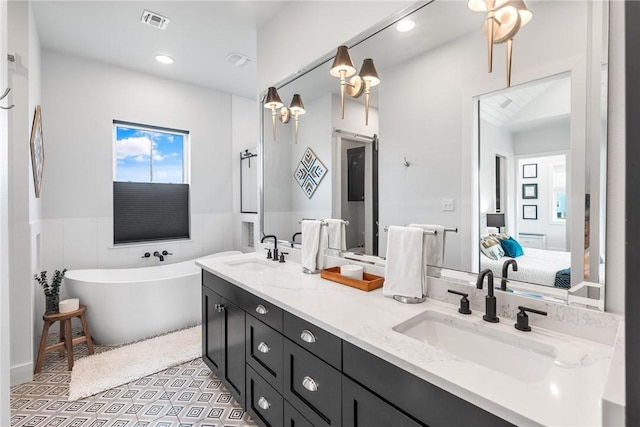 ensuite bathroom with a freestanding tub, ensuite bath, a sink, and visible vents