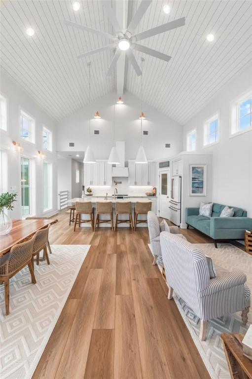 living room with high vaulted ceiling, wooden ceiling, light wood-style flooring, visible vents, and beam ceiling