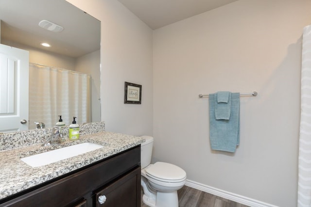 bathroom featuring vanity, wood finished floors, visible vents, baseboards, and toilet