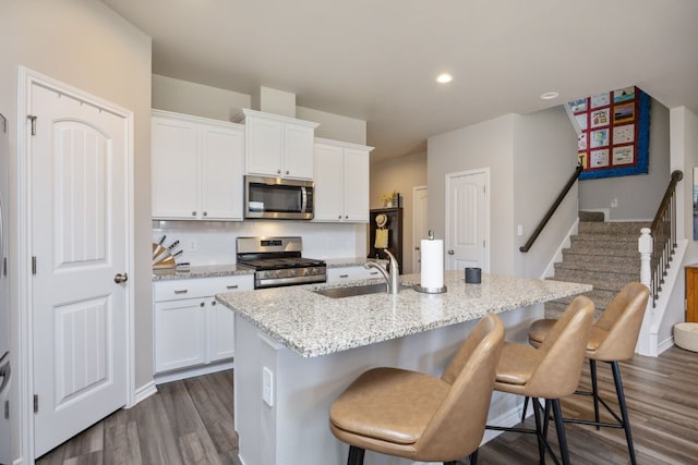 kitchen featuring a center island with sink, a sink, stainless steel appliances, a breakfast bar area, and decorative backsplash