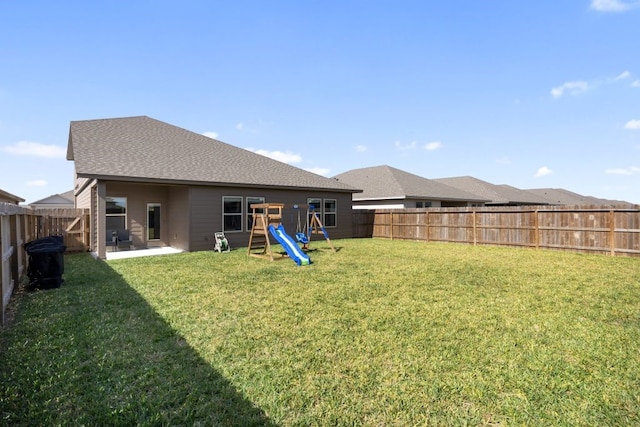 back of property featuring a playground, a lawn, and a fenced backyard