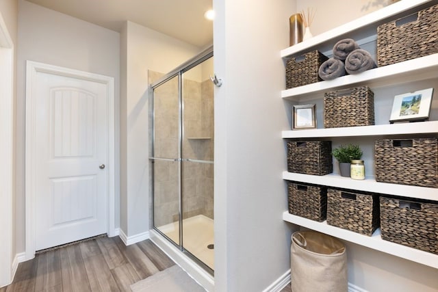 bathroom featuring a shower stall, wood finished floors, and baseboards