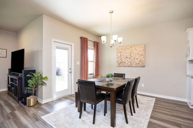 dining area featuring a notable chandelier, baseboards, and wood finished floors