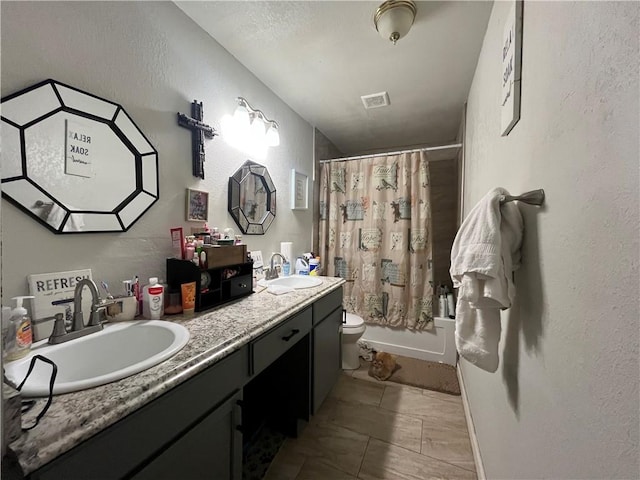 1253 Logan Ave, Corpus Christi, TX 78404 - full bath featuring toilet, double vanity, a textured wall, and shower / bath combo