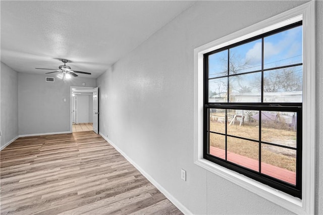 empty room featuring ceiling fan, a textured ceiling, and light wood-type flooring