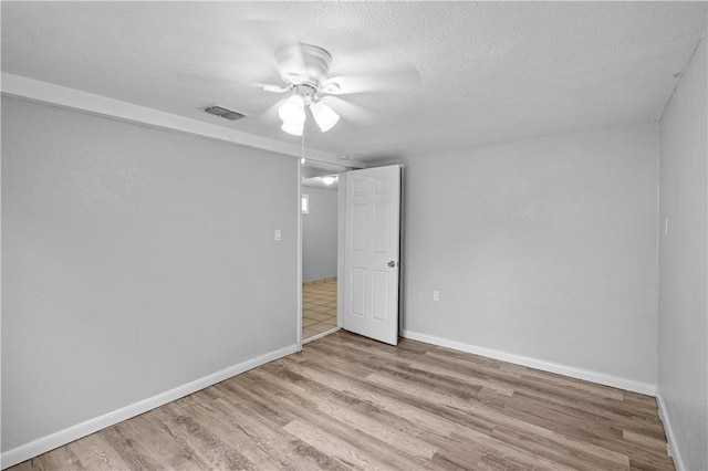 empty room with a textured ceiling and light wood-type flooring