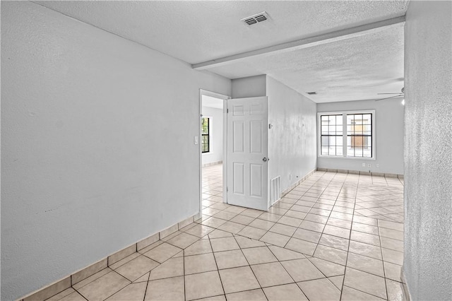 spare room with light tile patterned flooring, ceiling fan, plenty of natural light, and a textured ceiling