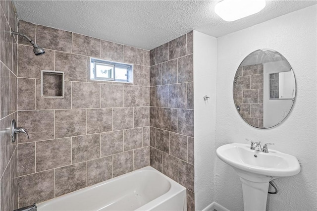 bathroom with tiled shower / bath, sink, and a textured ceiling