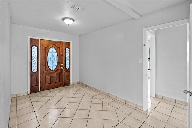 foyer entrance with beam ceiling, a textured ceiling, and light tile patterned flooring