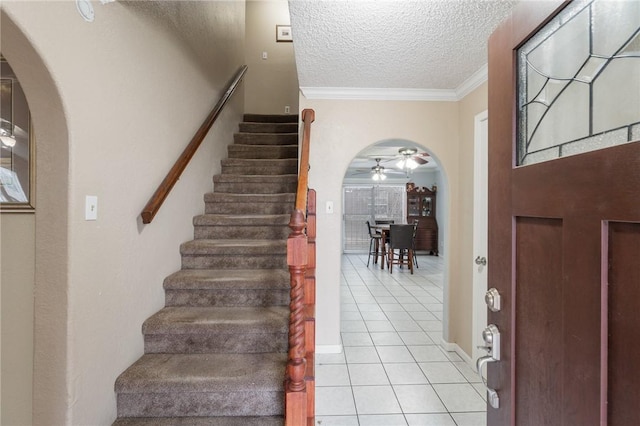 foyer entrance with a textured ceiling, ceiling fan, light tile patterned floors, and crown molding