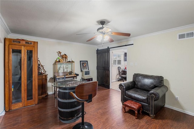 interior space with a barn door, dark hardwood / wood-style floors, and ornamental molding