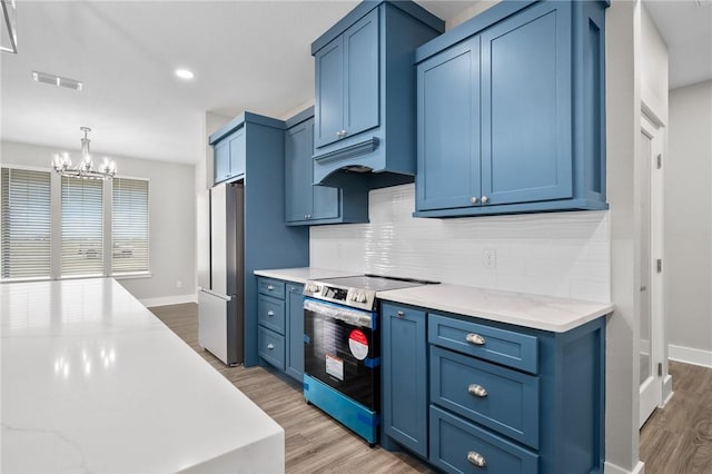 kitchen featuring a chandelier, blue cabinets, light wood-type flooring, and appliances with stainless steel finishes