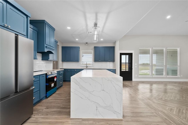 kitchen with sink, decorative backsplash, blue cabinetry, appliances with stainless steel finishes, and a kitchen island