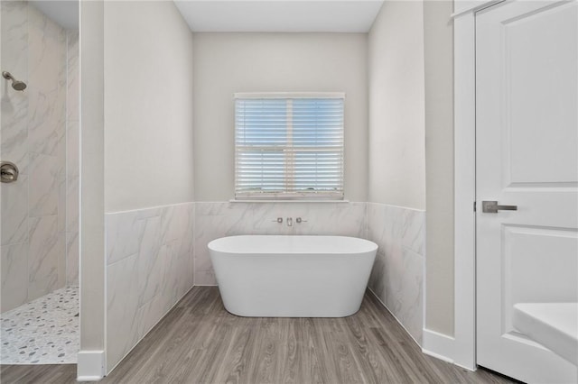 bathroom featuring shower with separate bathtub, hardwood / wood-style flooring, and tile walls