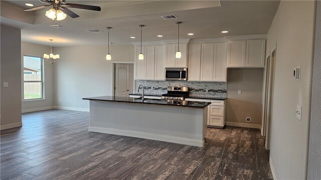 kitchen with dark wood-type flooring, white cabinets, tasteful backsplash, a kitchen island with sink, and appliances with stainless steel finishes