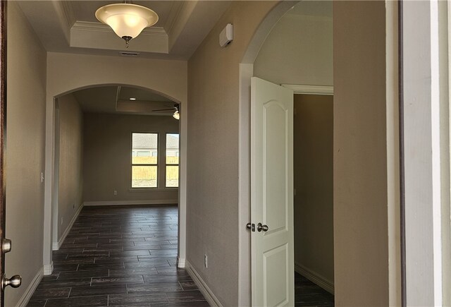 hall with dark hardwood / wood-style floors, a raised ceiling, and crown molding