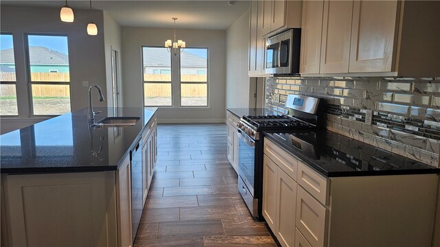 kitchen featuring stainless steel appliances, a center island with sink, sink, and pendant lighting