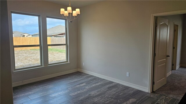 spare room featuring dark hardwood / wood-style floors, a healthy amount of sunlight, and an inviting chandelier