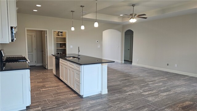 kitchen with pendant lighting, ceiling fan, a kitchen island with sink, white cabinets, and dark wood-type flooring