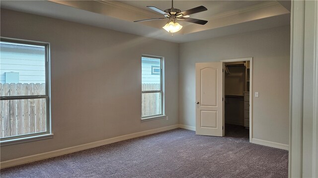 unfurnished bedroom with ornamental molding, ceiling fan, a spacious closet, carpet, and a closet