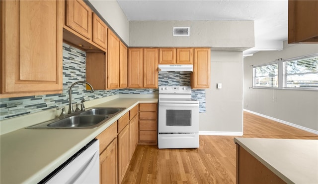 kitchen with tasteful backsplash, white appliances, sink, and light hardwood / wood-style floors