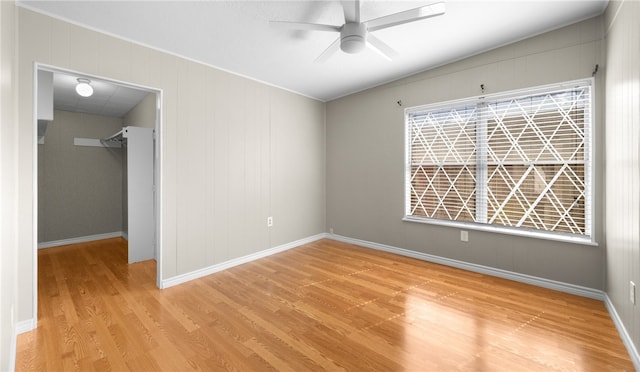 unfurnished bedroom with light wood-type flooring, a spacious closet, ceiling fan, and a closet