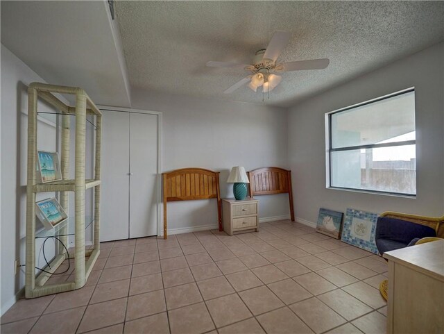 5973 State Highway 361 Unit 433, Port Aransas, TX 78373 - unfurnished bedroom featuring a textured ceiling, light tile patterned floors, ceiling fan, and baseboards