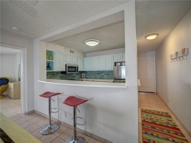 5973 State Highway 361 Unit 433, Port Aransas, TX 78373 - kitchen with appliances with stainless steel finishes, light tile patterned floors, decorative backsplash, open shelves, and a textured ceiling