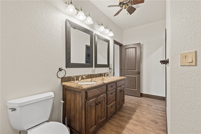 bathroom with hardwood / wood-style floors, vanity, ceiling fan, and toilet